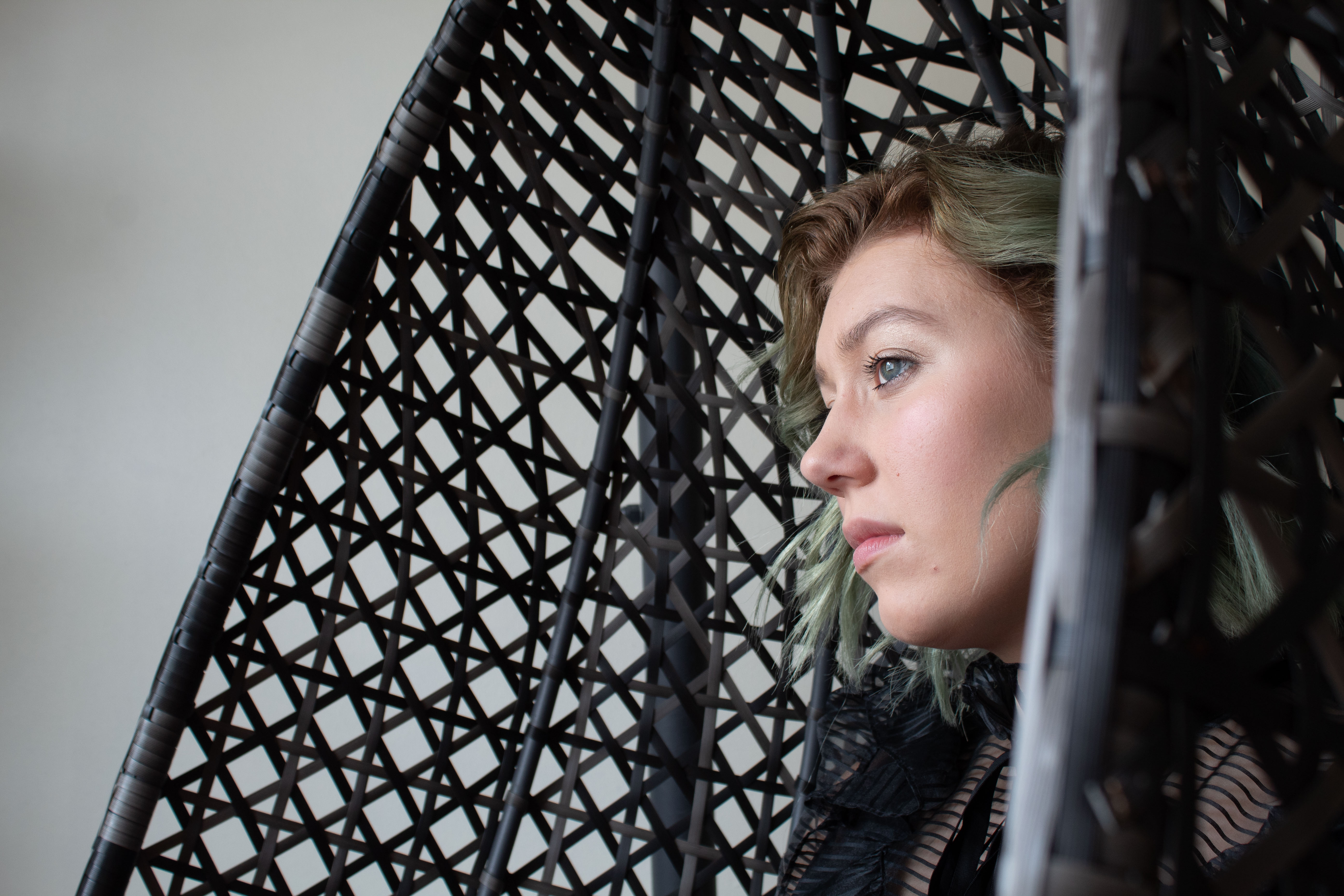 Woman in a wicker chair staring into distance, image by Kyle Knitter
